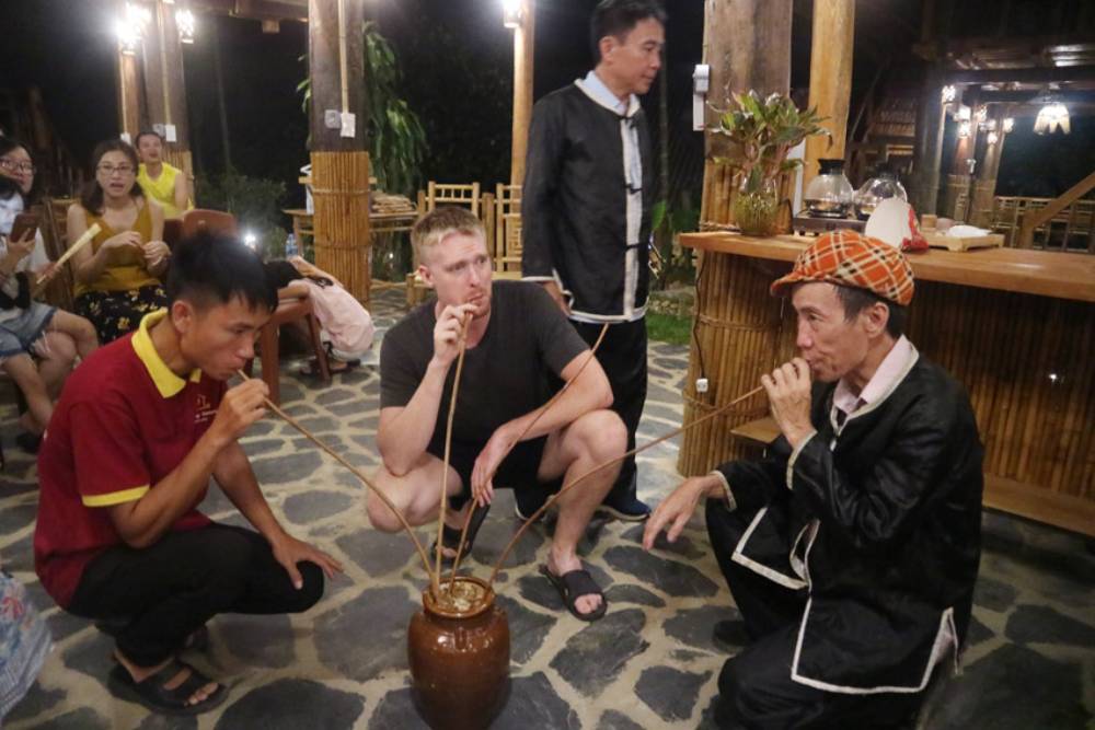Touristes dégustant le rượu cần Thaï à Pù Luông